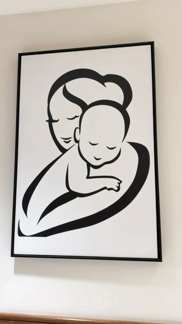 A framed line drawing hanging in the hospital: a mother in profile cradling a sleeping baby against her shoulder, drawn in a single continuous black line on white.