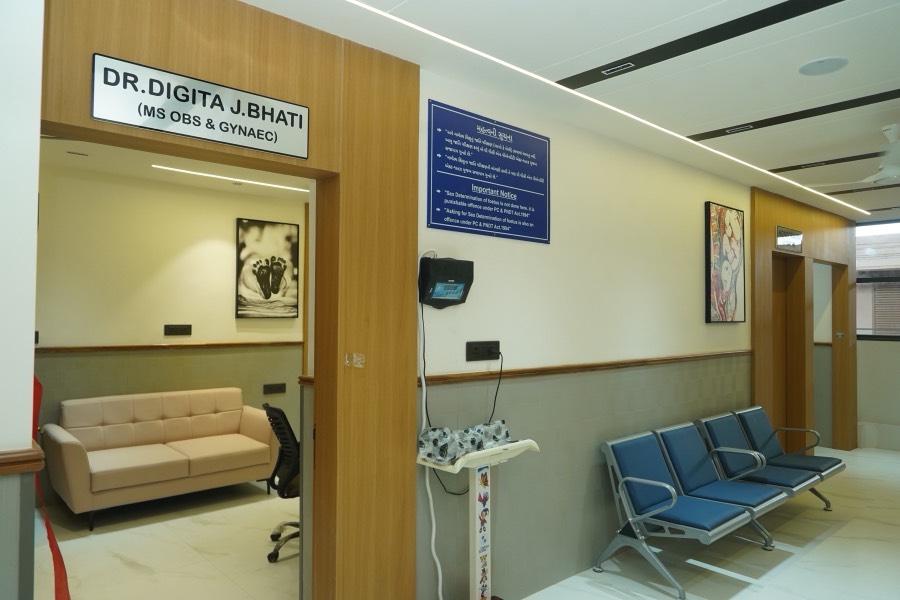 The gynaecology OPD corridor, with Dr. Digita J. Bhati’s nameplate above the consulting-room door, a cream sofa and blue waiting chairs.