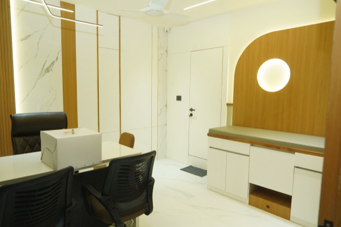 The counselling room, with a meeting table and an arched teak niche holding a soft round light.
