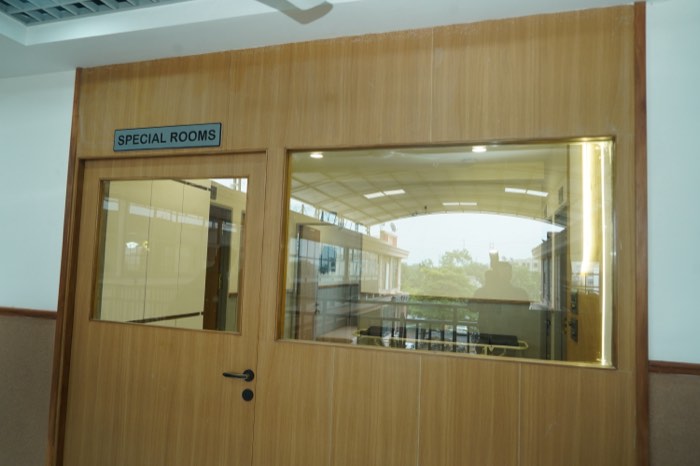 A glazed teak door signed “Special Rooms”, with daylight and treetops visible through the window beyond.