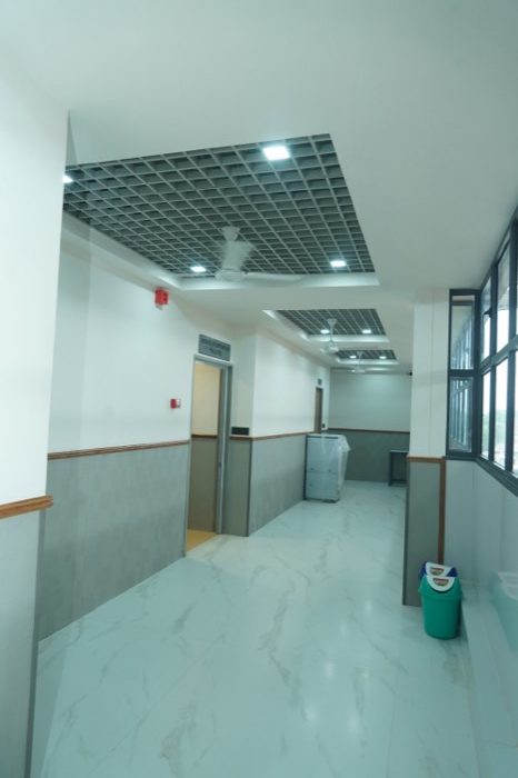 A bright upper-floor corridor with marble floors, a teak dado rail and a wall of windows on the right.