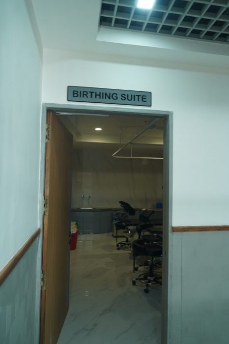 An open doorway beneath a sign reading “Birthing Suite”, looking into the prepared room beyond.
